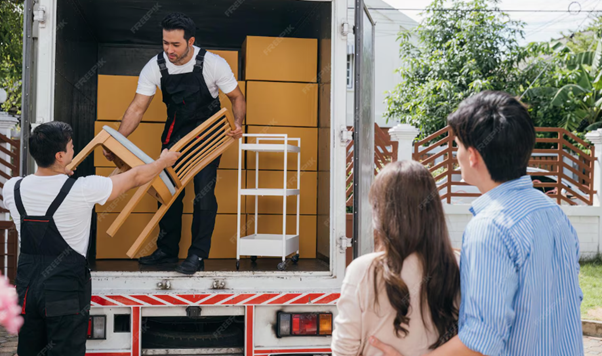 Movers unloading furniture and boxes for a couple moving house.